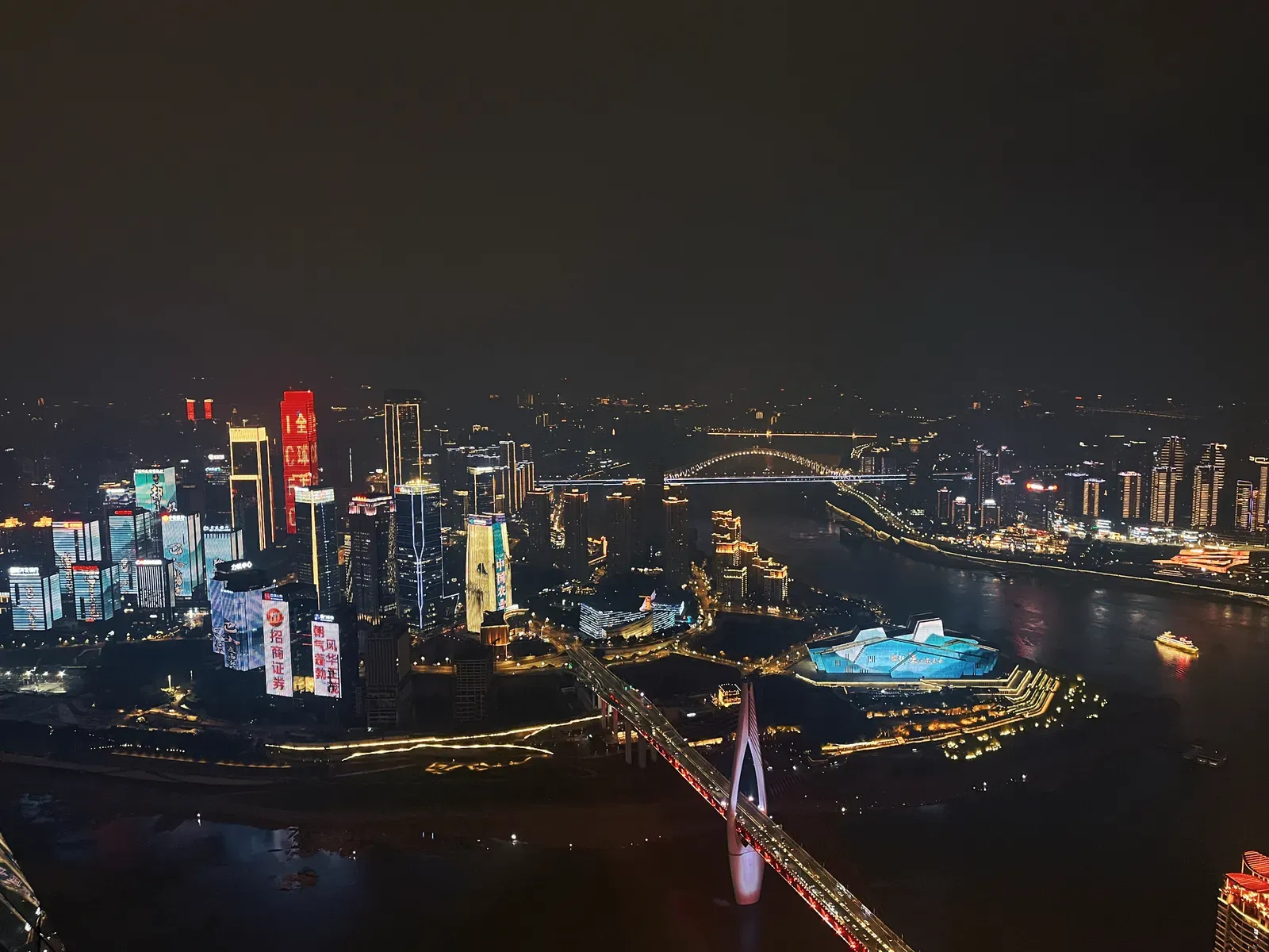 Night towers along a river fork, bridges lit in gold.